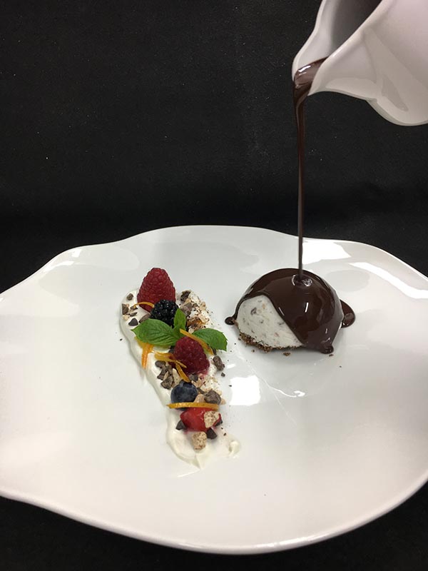 Semifreddo al torroncino (nougat parfait) served with warm chocolate sauce (70%) and spiced nougat chips